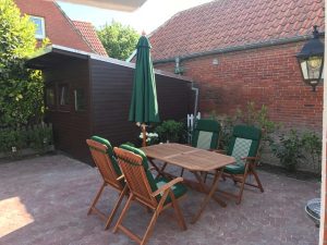 Sonnenschirm geschlossen, Gartentisch mit Stühlen in Holz.